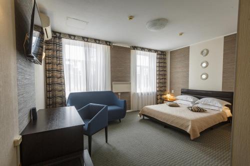 a hotel room with a bed and a blue chair at Sapporo Hotel in Khabarovsk
