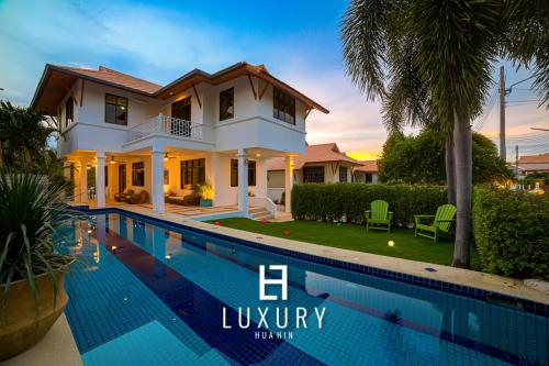 a villa with a swimming pool in front of a house at Modern Pool villa, 4 Bedroom Close to Beach - HV in Hua Hin