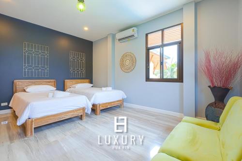 a bedroom with two beds and a couch and a window at Modern Pool villa, 4 Bedroom Close to Beach - HV in Hua Hin
