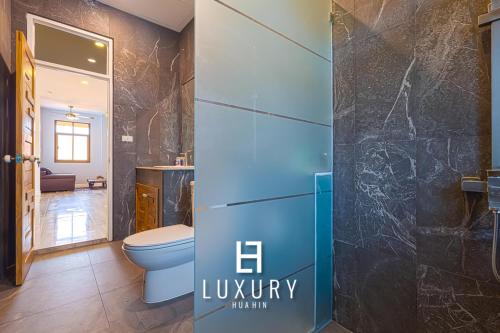 a bathroom with a toilet and a glass shower at Modern Pool villa, 4 Bedroom Close to Beach - HV in Hua Hin