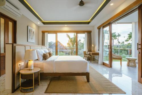 a bedroom with a bed and a large window at Villa Reillo By Nakula in Canggu