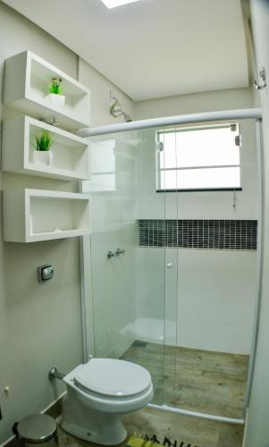 a bathroom with a toilet and a glass shower at Suítes Aconchego in Capitólio