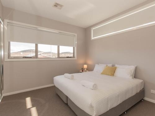 1 dormitorio con 1 cama blanca grande y ventana en 43A Twynam Street, en Jindabyne
