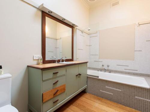 ein Badezimmer mit einem Waschbecken, einer Badewanne und einem Spiegel in der Unterkunft BEACHSIDE GETAWAY DROMANA in Dromana