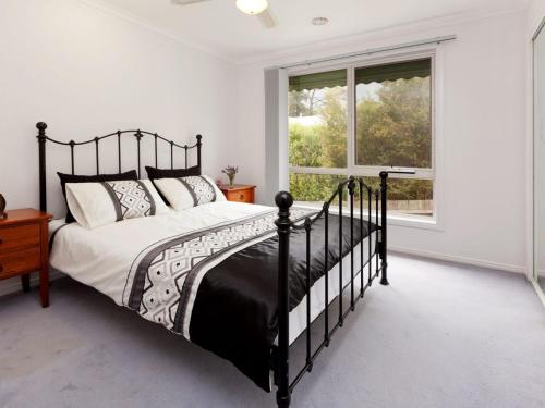 a bedroom with a black bed and a window at Dromana Bay Views Dromana in Dromana