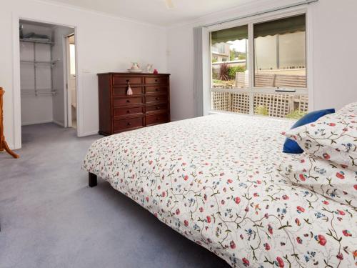 a bedroom with a bed and a dresser and a window at Dromana Bay Views Dromana in Dromana