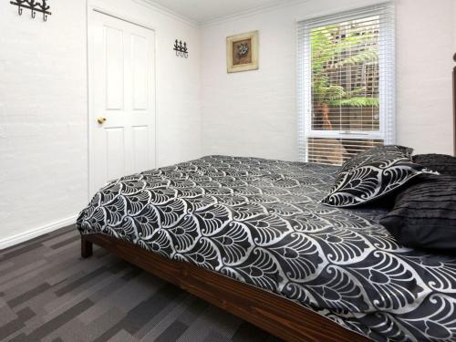 a bedroom with a bed with a black and white comforter at Dromana Bay Views Dromana in Dromana