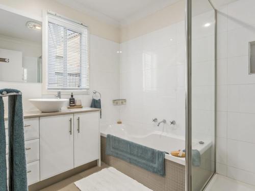 a white bathroom with a tub and a sink at Karinya Mornington in Mornington