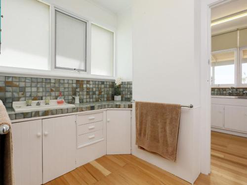 a kitchen with white cabinets and a sink at DROMANA BEACH SHACK in Dromana