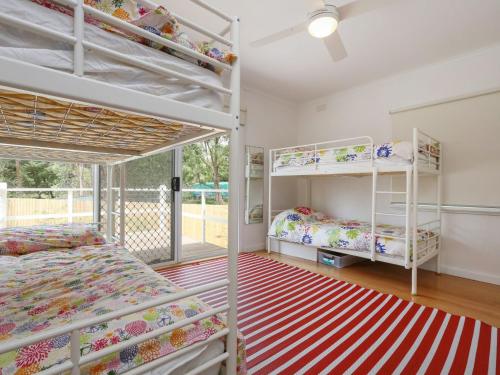 a bedroom with two bunk beds and a balcony at DROMANA BEACH SHACK in Dromana