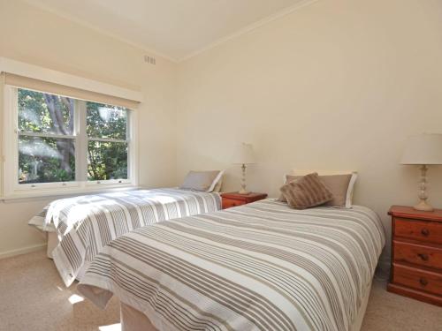 two beds in a white room with a window at Bay Views On Browne in Dromana