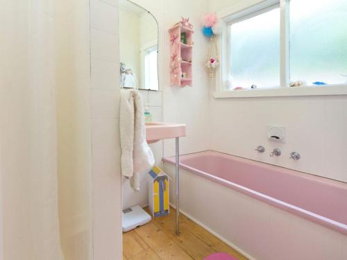 Baño de color rosa con bañera y lavamanos en Home Sweet Home Mount Martha en Mount Martha