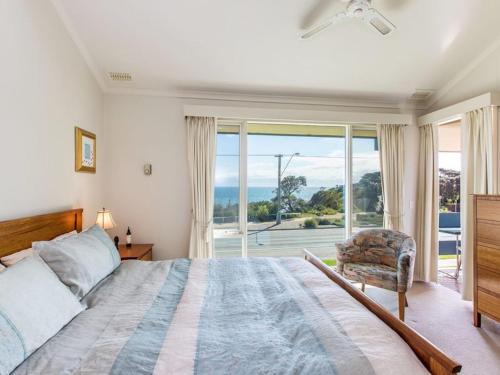 a bedroom with a bed and a large window at Seaviews Mornington in Mornington