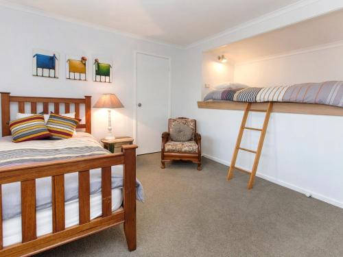 a bedroom with two bunk beds and a chair at Moonah Sands Rye in Rye