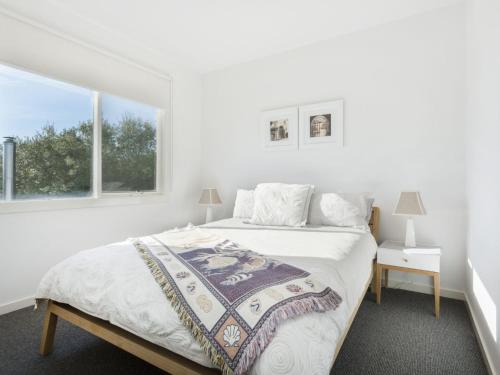 a white bedroom with a bed and a window at Sunset Views Mornington in Mornington