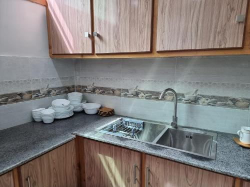 a kitchen counter with a sink and wooden cabinets at Srinagar Homes in Muzaffarabad
