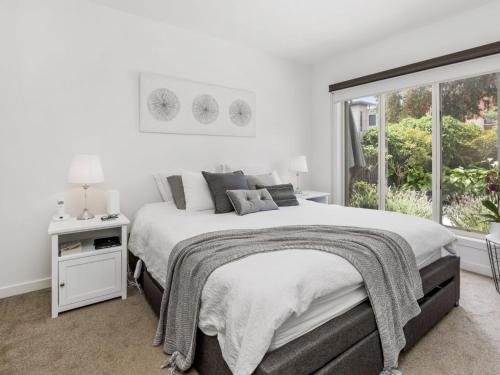 a white bedroom with a large bed and a window at Bangalow Mornington in Mornington