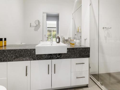 莫寧頓的住宿－Bangalow Mornington，白色的浴室设有水槽和淋浴。