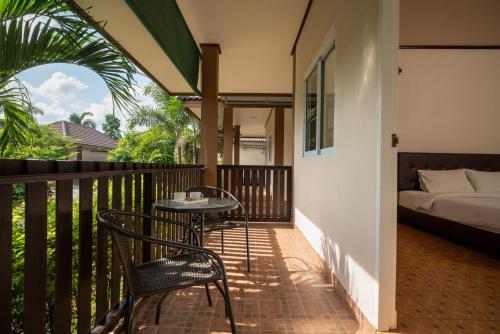 a balcony with a bed and a table and chairs at Bantung Resort in Sukhothai