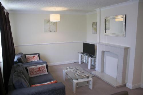 a living room with a fireplace and a chair and a tv at Carvetii - Uriah House - 4-Bedroom House sleeps up to 10 people in Belle Vue