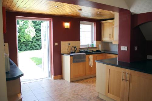a kitchen with wooden cabinets and a door to a yard at Carvetii - Uriah House - 4-Bedroom House sleeps up to 10 people in Belle Vue