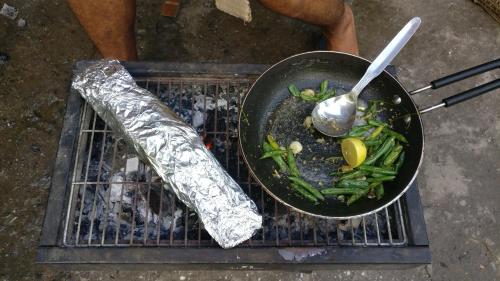a pan of food on a grill with a spoon at Flipsyde Retreat in Kasol