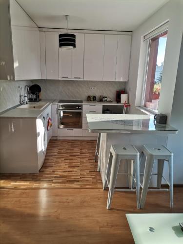 a kitchen with white cabinets and a wooden floor at Апартамент Стил in Velingrad