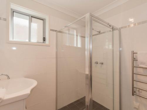 a white bathroom with a shower and a sink at Aspect 1 8a Poley Cow Lane in Jindabyne