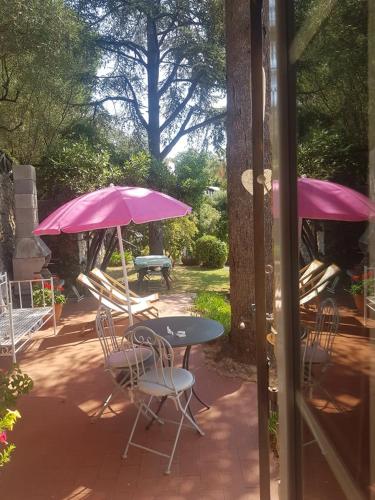 a table and chairs with pink umbrellas on a patio at IL NIDO DI KIKI Affittacamere BIKE &FUN in Finale Ligure