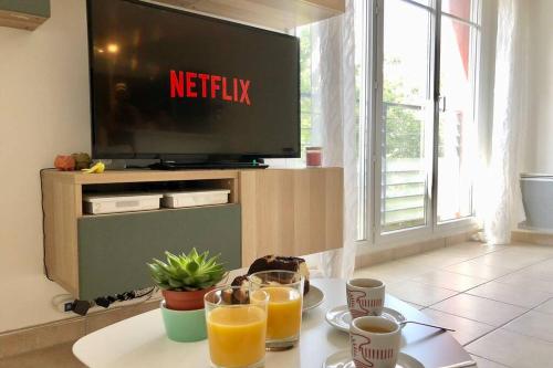 a table with two glasses of orange juice and a television at La suite nature Disneyland Paris in Montévrain