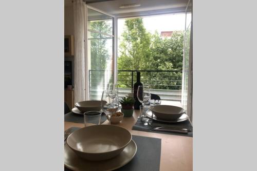 a table with plates and wine glasses and a window at La suite nature Disneyland Paris in Montévrain