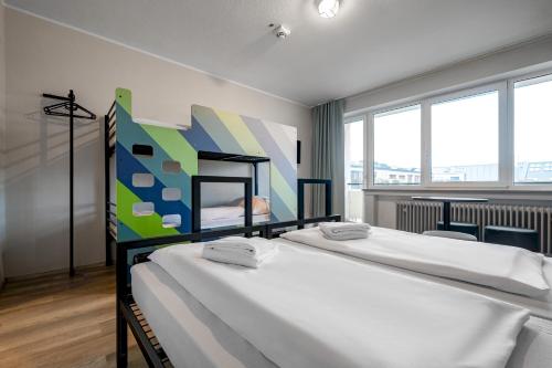 een slaapkamer met 2 bedden en een schilderij aan de muur bij a&o München Hauptbahnhof in München