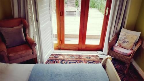 a room with a door and two chairs and a bed at High Hopes in Greyton