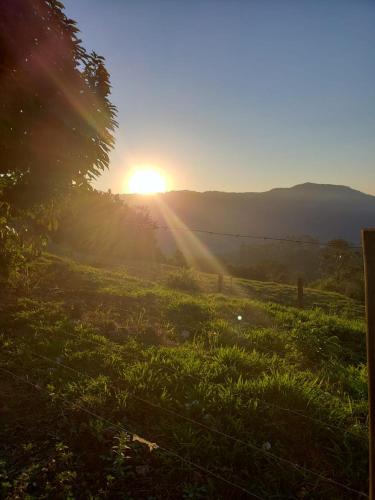 a sunset in a field with the sun shining on the horizon at Casa de campo Rosa dos ventos in Rodeio