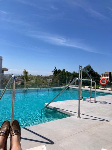 a persons feet in sandals sitting next to a swimming pool at Luxury Penthouse Pedro - The View Fuengirola in Fuengirola