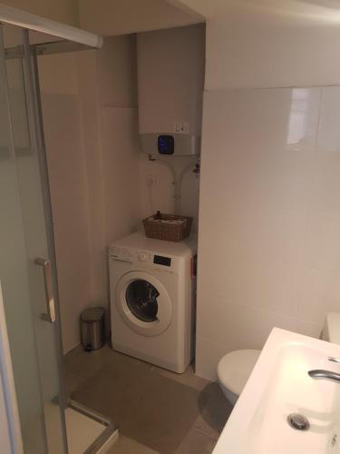 a small bathroom with a washing machine and a toilet at Charmant 2 pièces en plein coeur du village in Cargèse