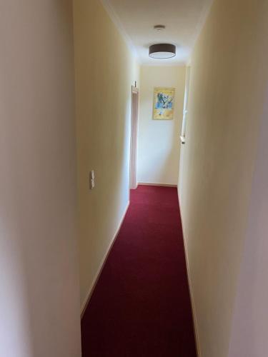 an empty hallway with a red carpet and a door at Gasthof zur Post - Standort Am Bahnhof Eiserfeld in Siegen