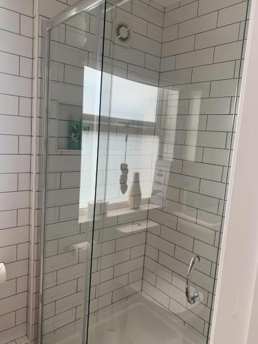 a shower with a glass door in a bathroom at Perfect base for 8, pets allowed in Tenby