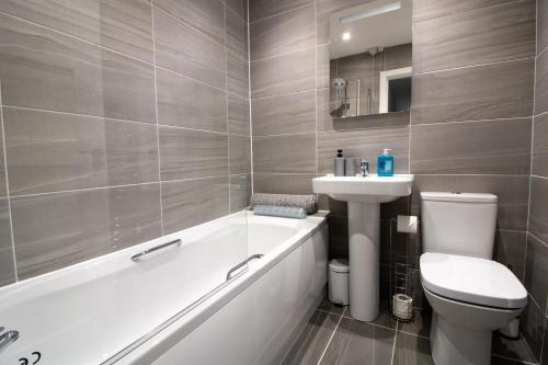 a bathroom with a tub and a toilet and a sink at Modern and Stylish Apartment- Short Walk to Beach in Paignton