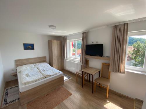 a bedroom with a bed and a desk and a television at Vila Zdravković Prolom Banja in Prolomska Banja