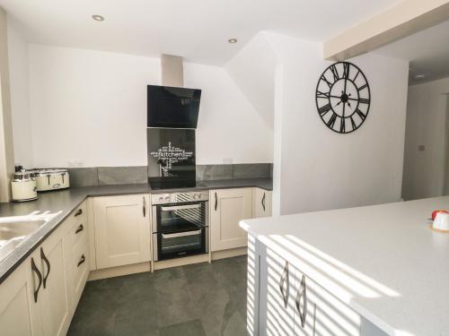 a kitchen with white cabinets and a clock on the wall at 26 Hycemoor Way in Millom