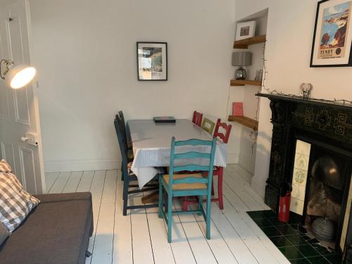 a dining room with a table and chairs and a fireplace at Hobbes Cottage, pets allowed in Tenby