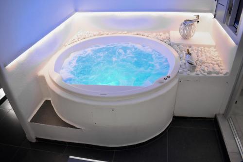 a bath tub with a pool of blue water in it at Ariana Eco Suites Adults Only in Fira