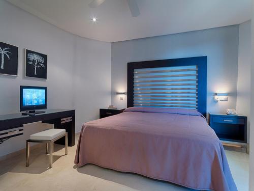 Dormitorio con cama, escritorio y TV en Anfi del Mar Tauro Golf 1 Emerald Club, en Mogán