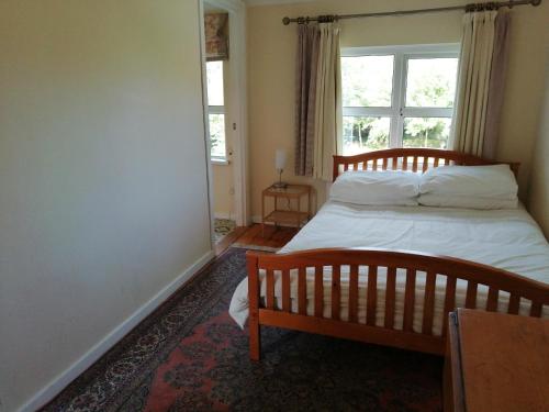 a bedroom with a bed and a window at Lisieux House on Lough Neagh in Aghalee
