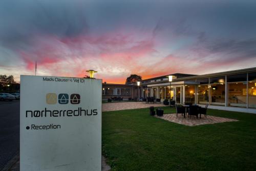 a sign in front of a building with a sunset at Hotel Nørherredhus in Nordborg