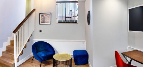a living room with blue chairs and a table at One Shot Conde Torrejón in Seville