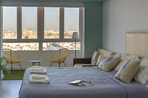 1 dormitorio con cama, sofá y ventanas en ATLANTICO Family Home by Cadiz4Rentals, en Cádiz