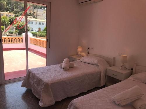 a bedroom with two beds and a large window at Puerto Pollensa Villa Nevada next to the Beach, private pool in Port de Pollensa