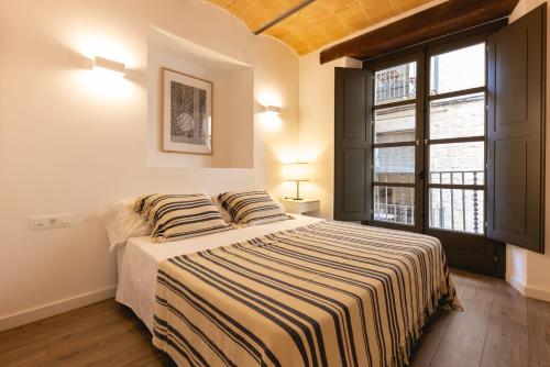 - une chambre avec un lit avec des draps rayés et une fenêtre dans l'établissement Bravissimo Cort Reial Entresol B, à Gérone